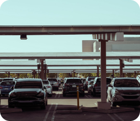 La photographie montre des ombrières photovoltaïques, distribuées par rangée sur un large parking. Des véhicules sont stationnés sous les ombrières photovoltaïques, à l'abri du soleil et des intempéries.