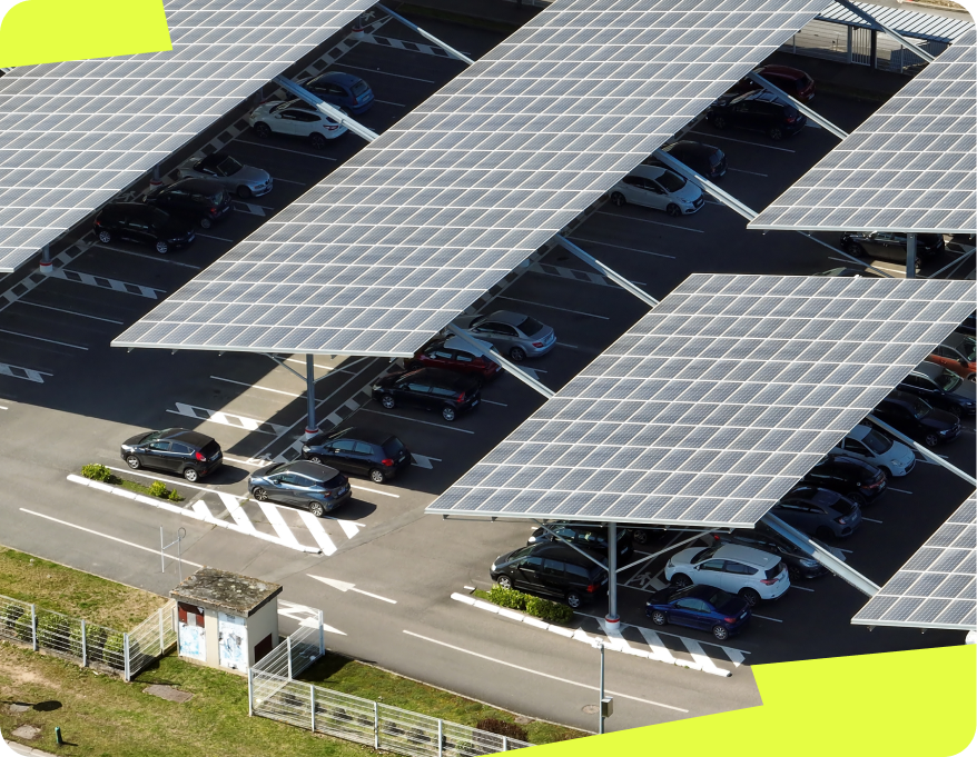 L’image montre un parking équipé de larges ombrières photovoltaïques. Les véhicules sont garés en dessous de ces structures, protégés du soleil et des intempéries. Les ombrières photovoltaïques sont réparties sur plusieurs rangées, couvrant une grande surface du parking.